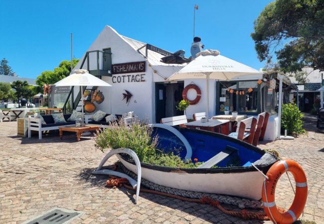 Ресторант Fisherman’s Cottage в Южна Африка – морска атмосфера с лодка и тераса на открито.