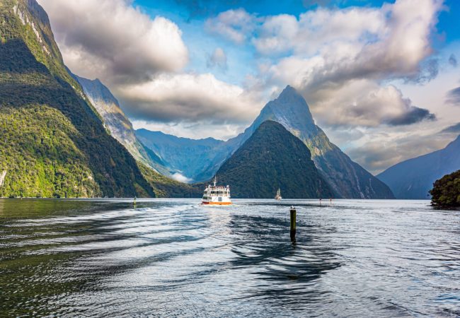 New Zealand. South Island. Tourist boat in the smooth water of the Milford Sound. Fiordland park.The magical nature of the southern hemisphere.